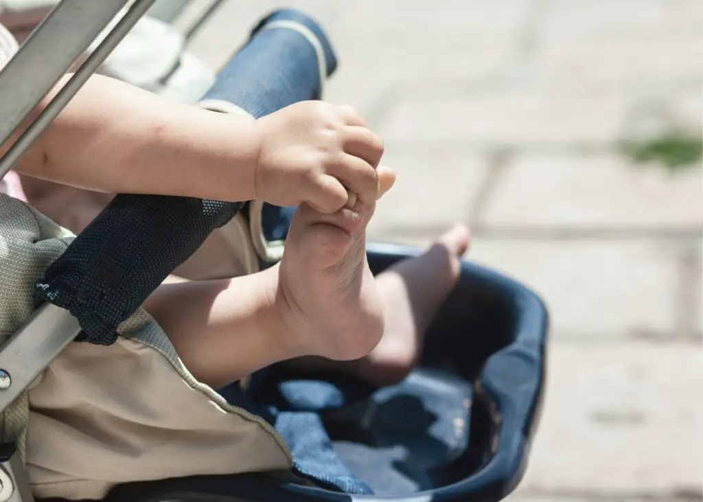 baby grabbing toes in stroller: get things done by taking baby with you