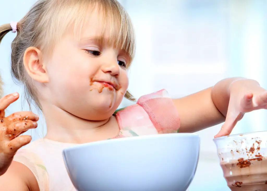 3 tear old girl with pigtails eating from a blue bowl and glass cup in front of her: 3 year old daily schedule