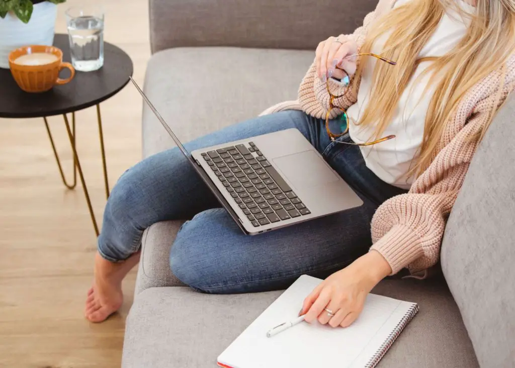 3 Year Old Schedule For Stay At Home Moms: mom sitting on couch with open laptop and planner pad next to her getting some work done while toddler has quiet time