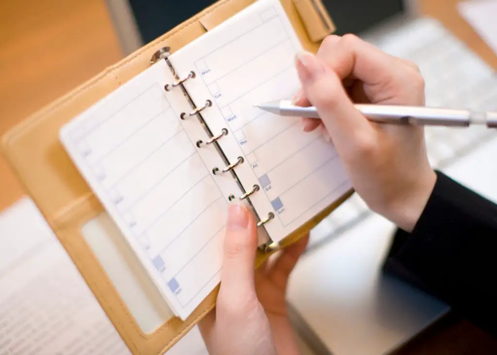 3 Year Old Schedule Stay At Home Mom: mom holding planner with pen in right hand