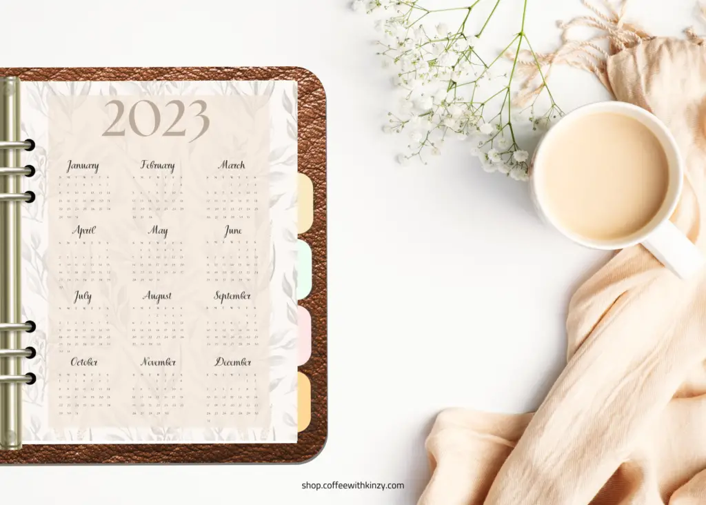 boho 2023 single page calendar: faded boho print and neutral colors, on table with baby's breath, cup of coffee and cozy blanket